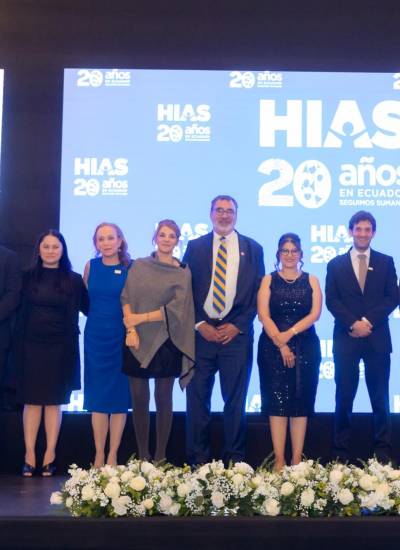 Sabrina Lustgarten, vicepresidenta ejecutiva de HIAS Ecuador (vestido azul); Mark Hetfield, CEO de HIAS (corbata amarilla con franjas azules) y a su lado, Maricela Parra, directora nacional de HIAS Ecuador. (vestido negro), junto a otras figuras destacadas de la organización en un evento de celebración.