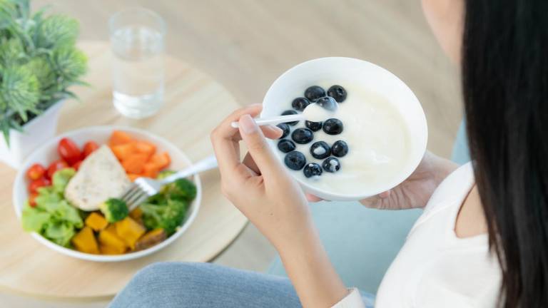Mujer consumiendo fibra a través de frutas con yogurt griego y vegetales.
