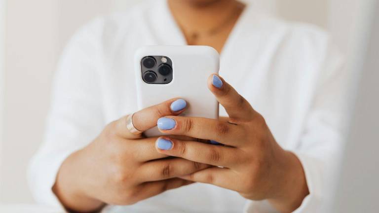 Mujer navegando en su dispositivo móvil iPhone.