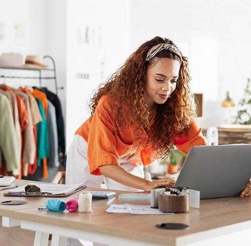 Mujer joven trabajando con inventario de ropa en casa como emprendimiento.