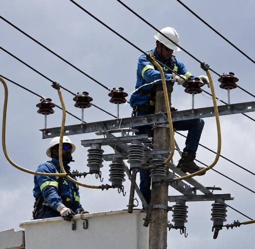 Imagen referencial que muestra a trabajadores de la Empresa Eléctrica de Quito (EEQ) arreglando un cable tensor.