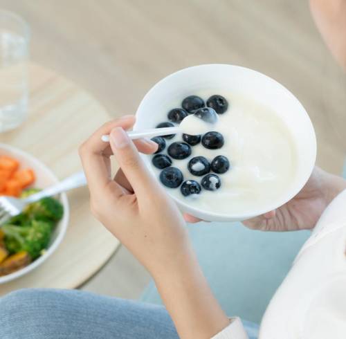 Mujer consumiendo fibra a través de frutas con yogurt griego y vegetales.
