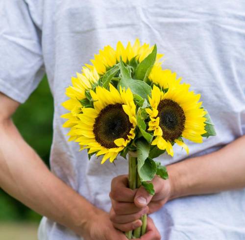 Imagen referencial de alguen regalando flores amarillas.