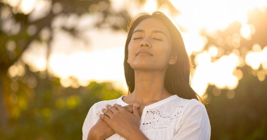 Mujer respirando profundamente en el aire libre.
