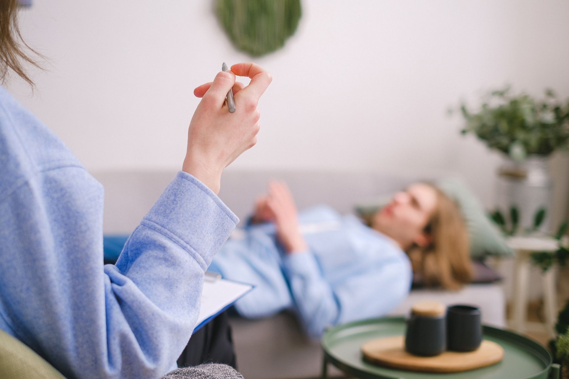 Terapeuta anotando durante uma sessão de terapia com um cliente relaxado deitado em um sofá.