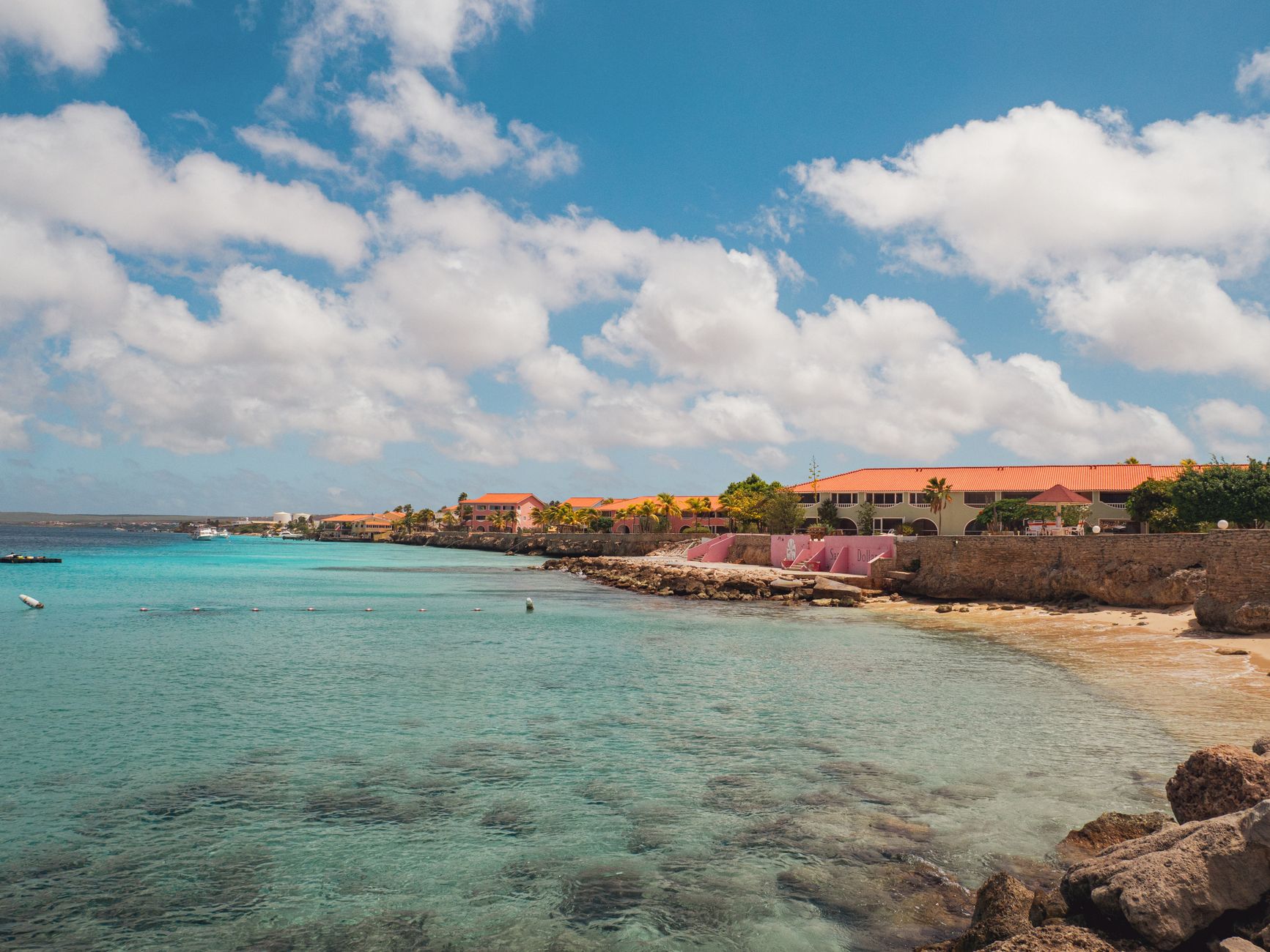 Praia pitoresca do Caribe com edifícios vibrantes ao longo da costa sob um céu azul claro.