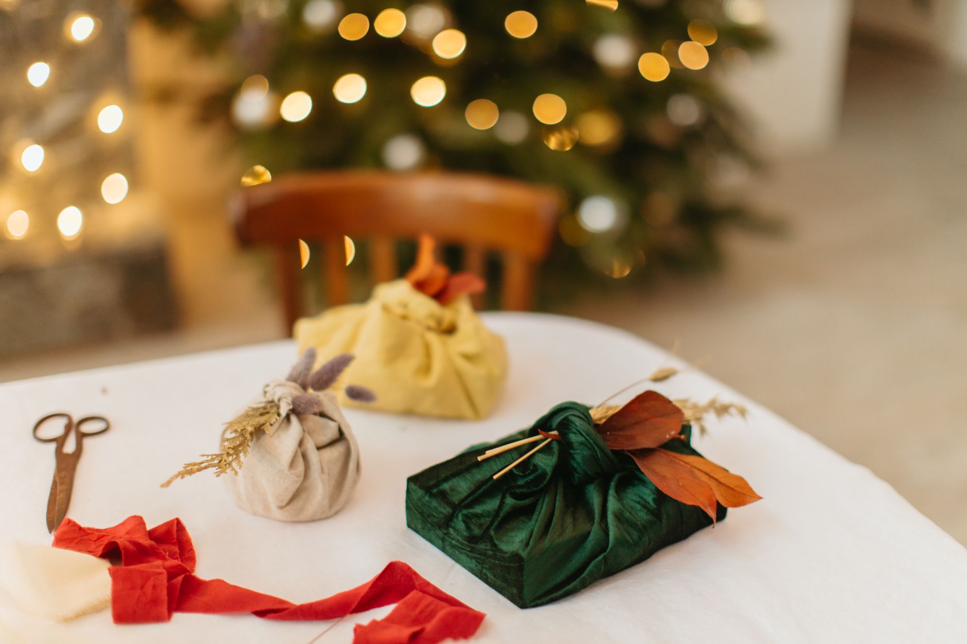 Presentes de Natal decorativos elegantemente embrulhados em uma mesa, cercados por luzes bokeh aconchegantes.